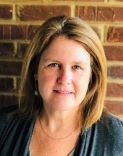 Portrait photo of Kelley Williams with brick wall in background