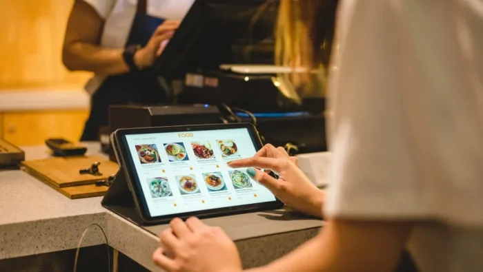Close-up of manicured hands making a selection on a digital food ordering tablet