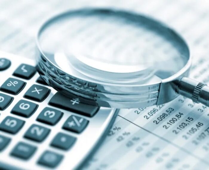 magnifying glass and calculator with spreadsheets