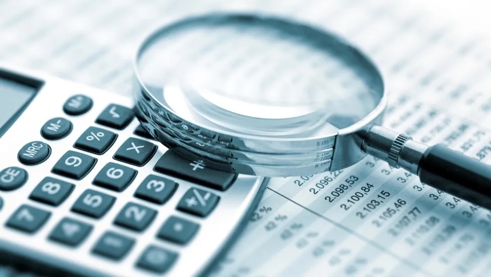 Magnifying glass and calculator sitting on top of a financial document