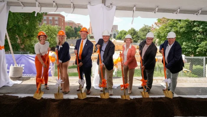 Haslam's seven deans use shovels to turn ceremonial dirt in front of the the site the new Haslam College of Business building will be located.|Ceremonial shovels decked with orange and white bows lean against a tabled with orange and white ceremonial hard hats on it.