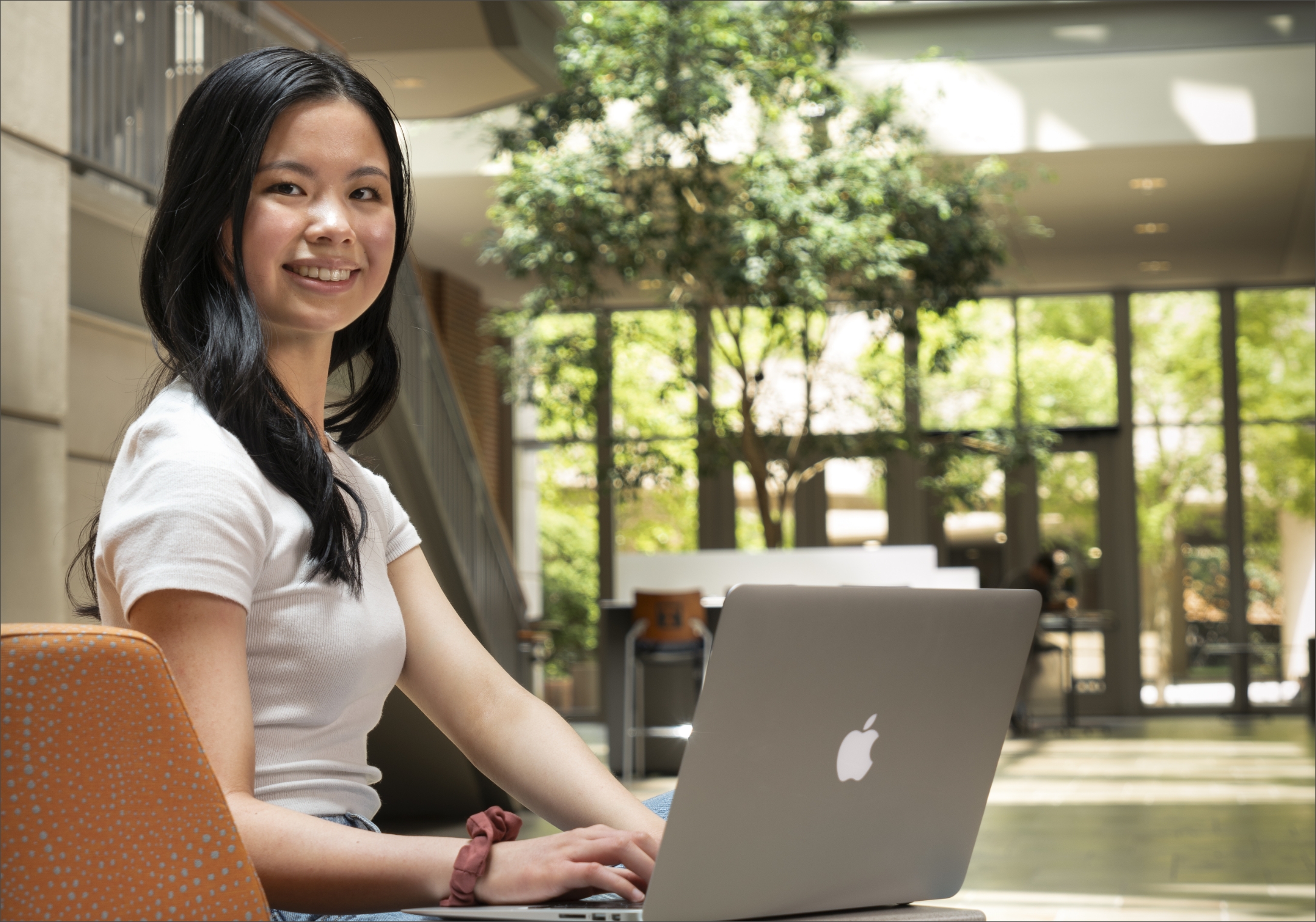 Woman working on a laptop in Haslam Business Building Atrium