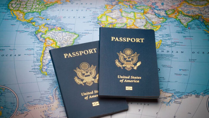 Two U.S. passports lie atop a world map.||