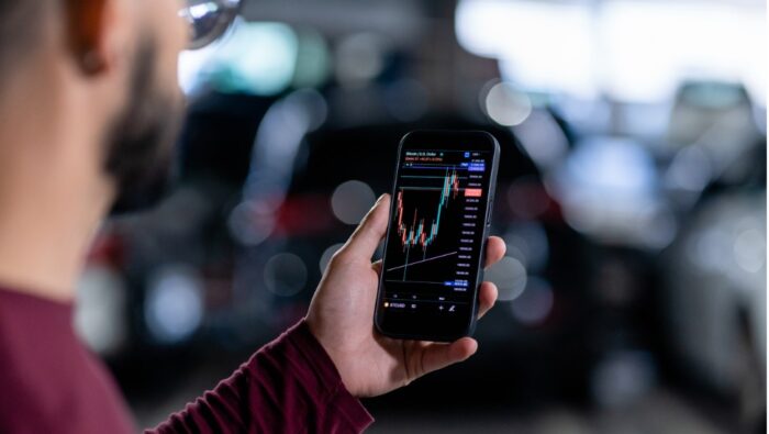 Male looks at investments on his smart phone